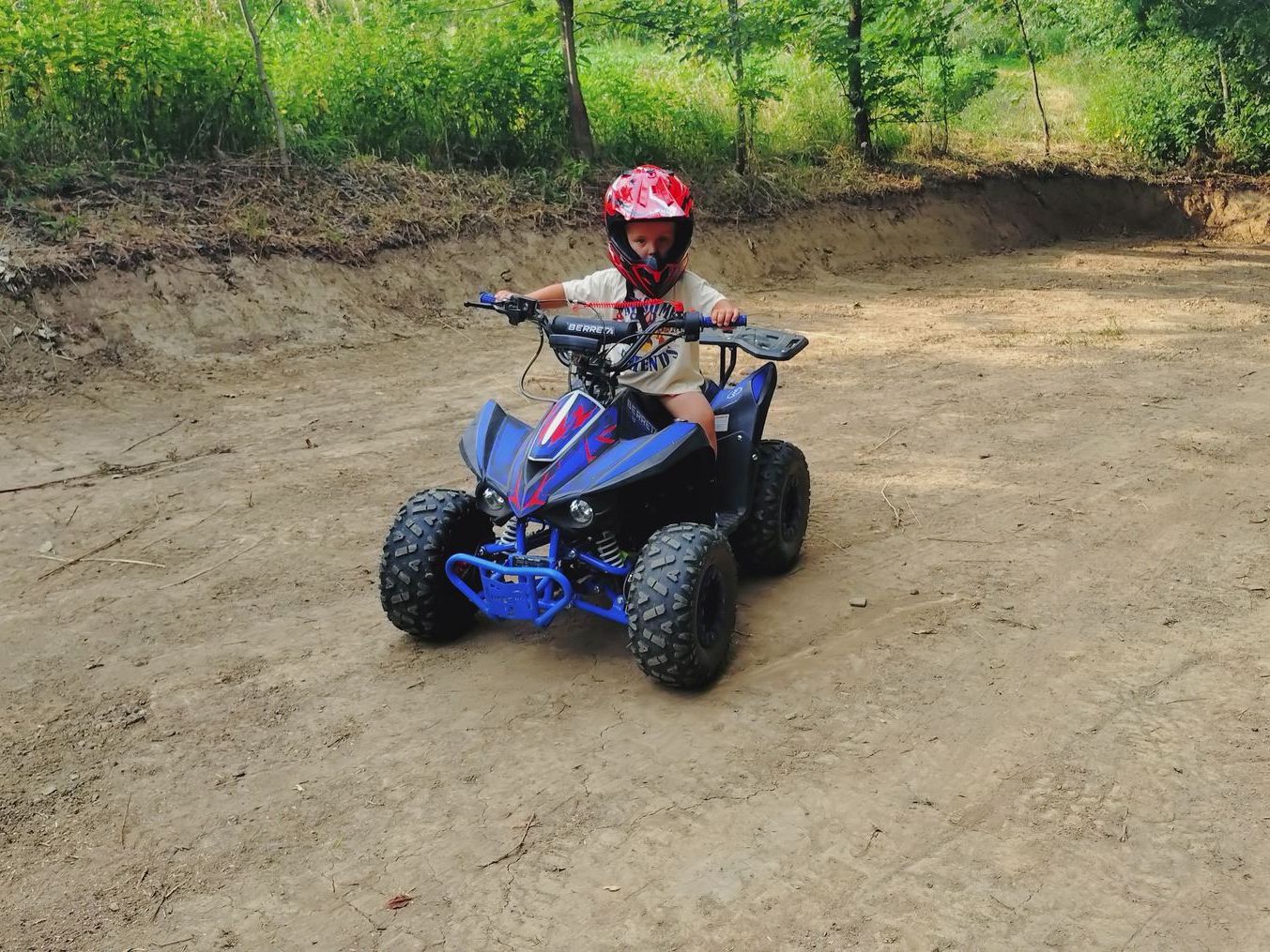 Dziecko w kasku na małym quadzie na zamkniętym torze Max Moto